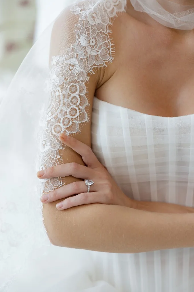 Close-up of a bride in lace veil and gown with pear-shaped diamond ring