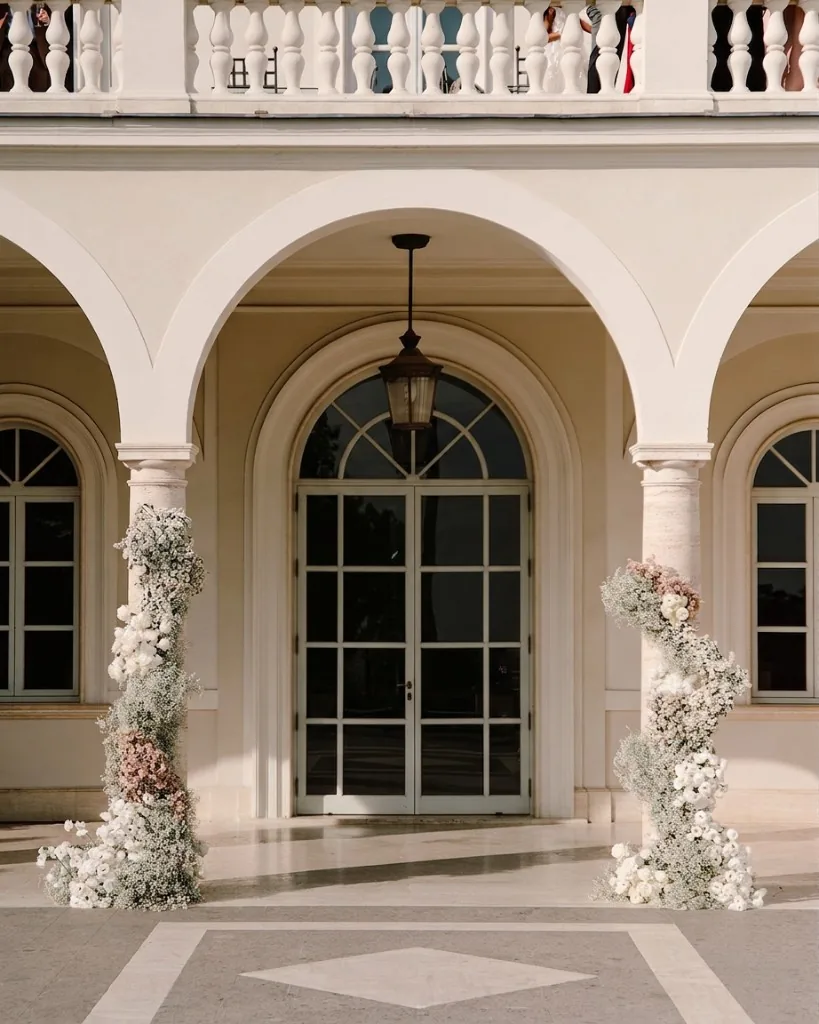 Villa Miani wedding entrance in Rome with arched portico, columns and abundant white and blush floral installations