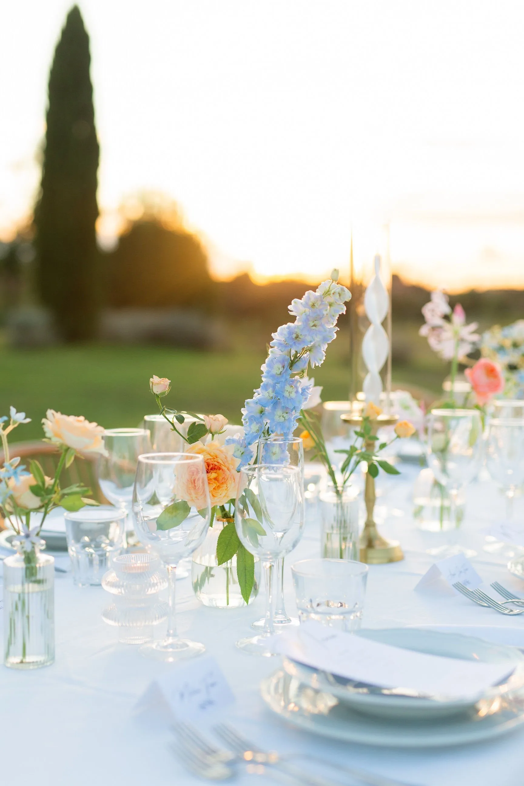 Long outdoor wedding table at Casale del Gallo against an ivy-covered villa: white linen, dahlias, sunflowers, pomegranates and taper candles in golden light