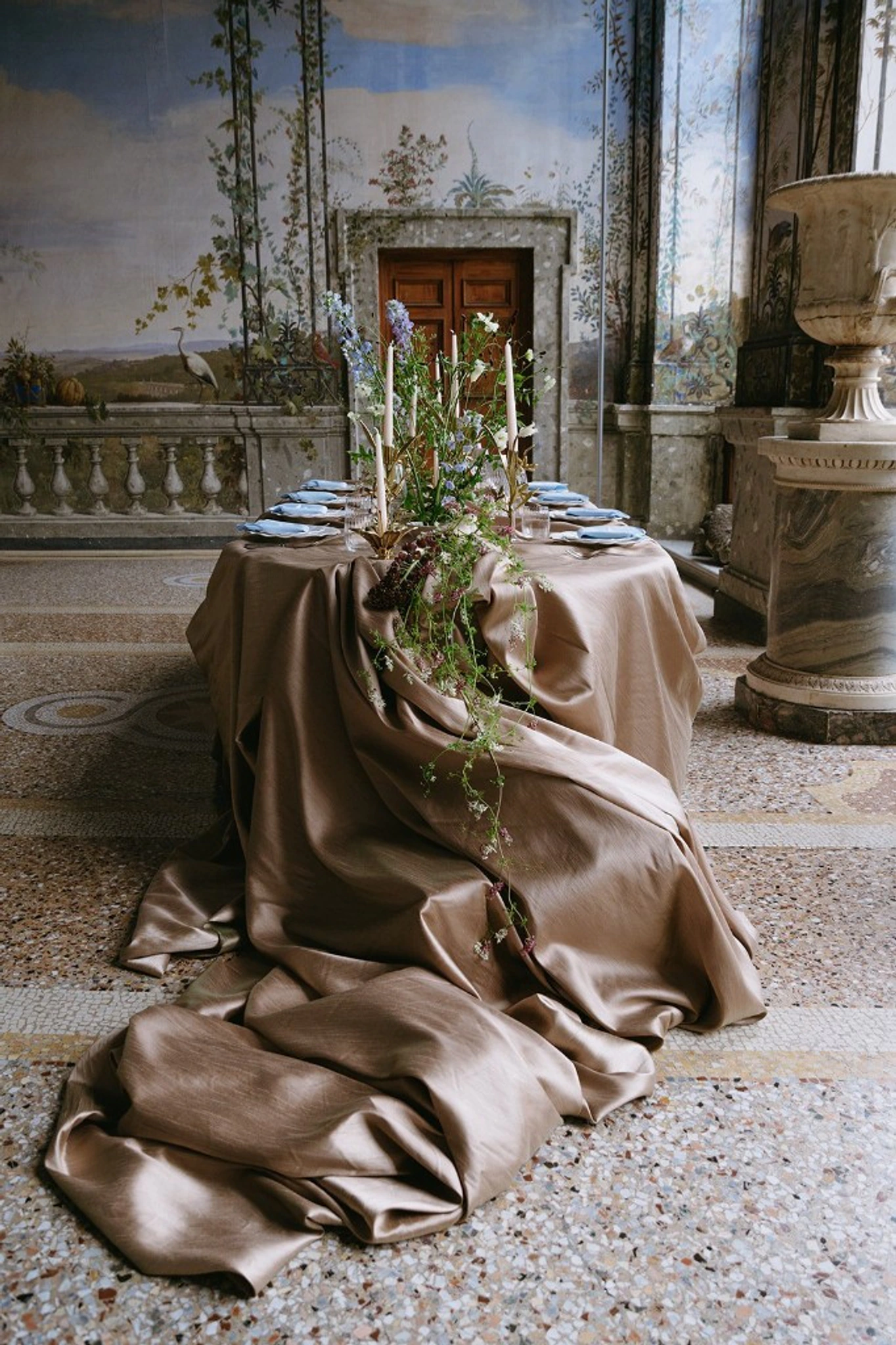 Palazzo wedding dining room in Rome frescoed walls mosaic floor long reception table with champagne drapery delphiniums candles and sky-blue accents